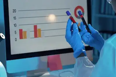 A doctor or scientist analyzing blood test results on a computer in a lab setting.